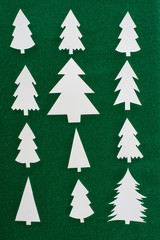top view of white paper christmas trees on green background