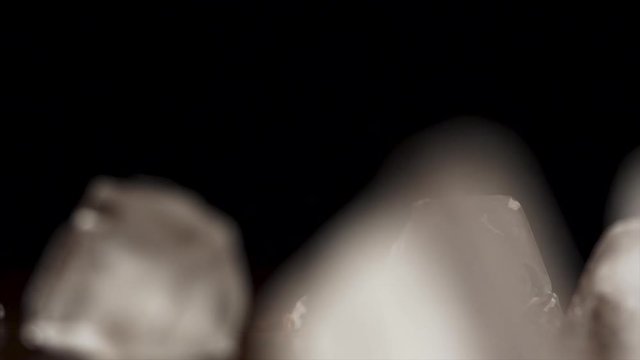 Ice cubes falling and bouncing on black background in slow motion. Ice drops on black background