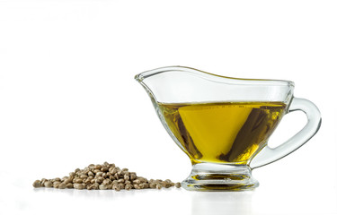 Hemp seeds and hempseed oil in a glass vessel isolated on a white background.