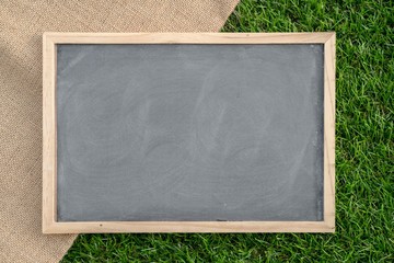 Abstract chalk blackboard with wood border frame on grass floor included copyspace ready used as background for add text or graphic