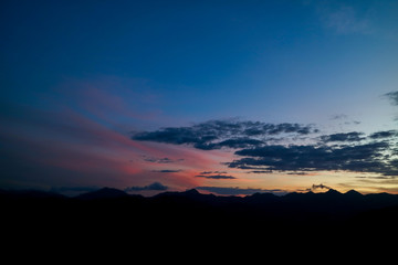 The ridge is a black silhouette. Sunset time. Use as background.