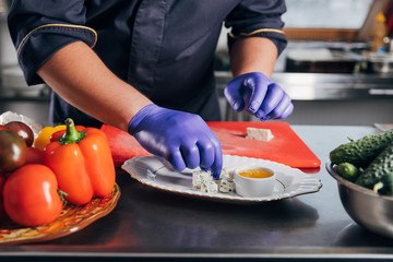 cropped shot of chef putting cheese pieces on plate