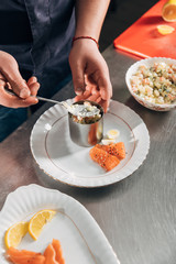 cropped shot of chef preparing salad with metal forming tube at restaurant