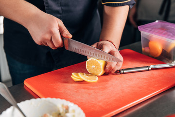 cropped shot of chef slicing lemon at restaurant