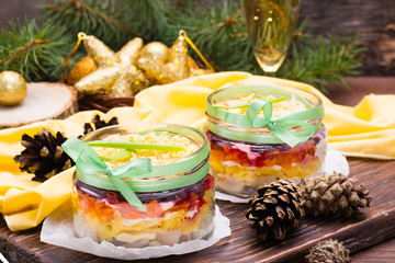 Obraz na płótnie Canvas Traditional Russian salad - herring under a fur coat in bowls in New Year's decorations