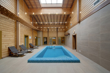 A sauna with wooden beams and high ceilings with a bath and the pool