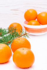 Ripe mandarins on a table and in a bowl and fir branches