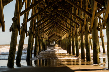 old american wood pier on sunny summer day with waves seen from below