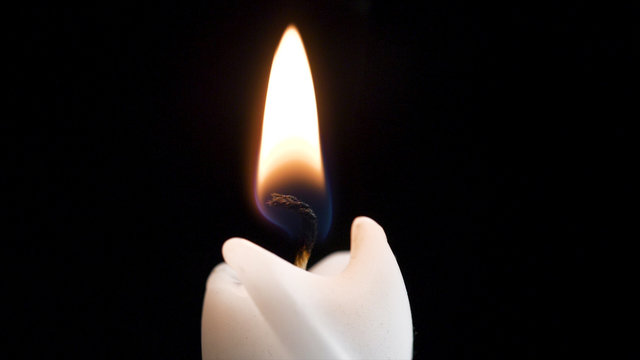 Close up detail of white wax lit candle flame and wick on isolated black background. andle lights macro. closeup of burning candle isolated on black background one flame at night macro brightly in