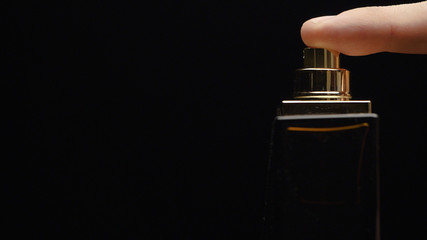Fragrance luxury bottle contents in dark spraying slow motion. Perfume bottle spray on black...