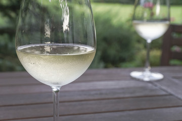 white wine glasses on wooden table at garden