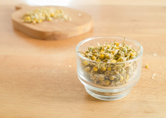 Dried Camomile in cup glass on wooden table