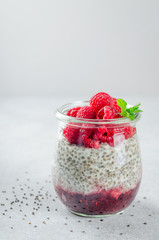 One glass of chia pudding with raspberry, jam and mint leaves on
