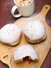 Pyszne pączki z cukrem pudrem i kubek kawy na drewnianym tle. Tłusty czwartek. 
