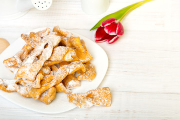 Faworki - Traditional Polish cookies served at Fat Thursday.  Cookies and tulip bouquet on white wooden background