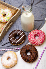 Bottle of milk and colorful donuts with chocolate and icing, selective focus