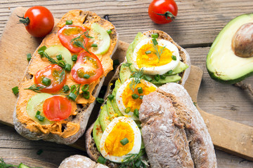 Sandwiches with avocado, eggs and tomato on a wooden background. Fresh organic vegetables, eggs and whole wheat bread. Healthy breakfast. Retro style.