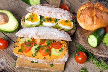 Sandwiches with avocado, eggs and tomato on a wooden background. Fresh organic vegetables, eggs and whole wheat bread. Healthy breakfast. Retro style.
