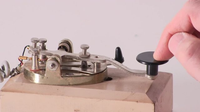 Isolated close-up shot of finger pressing telegraph key sending morse code radio transmission message