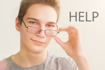 Portrait of attractive young man teenager looking at camera and smiling with inscription HELP at background.