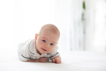 Cute little four month old baby boy, playing at home in bed