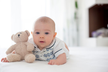 Cute little four month old baby boy, playing at home in bed