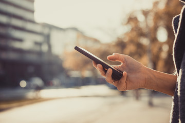 Typing message on mobile phone in the city.