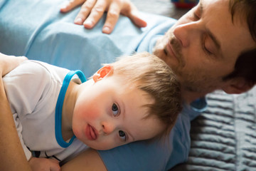 Fototapeta premium Cute baby boy with Down syndrome playing dad on in home living room