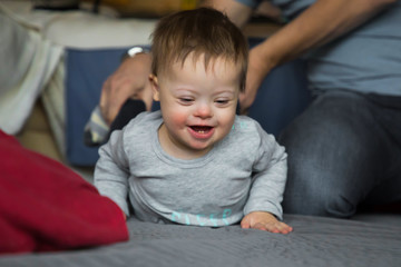 Fototapeta premium Cute baby boy with Down syndrome playing with dad on in home living room