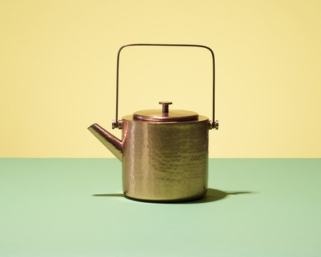 Copper tea kettle with yellow background