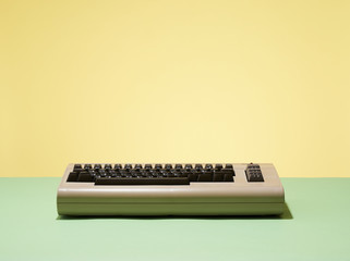 Computer keyboard of video gaming console against yellow background