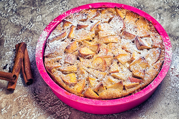 charlotte pie on a plate, with sugar and cinnamon rolls.