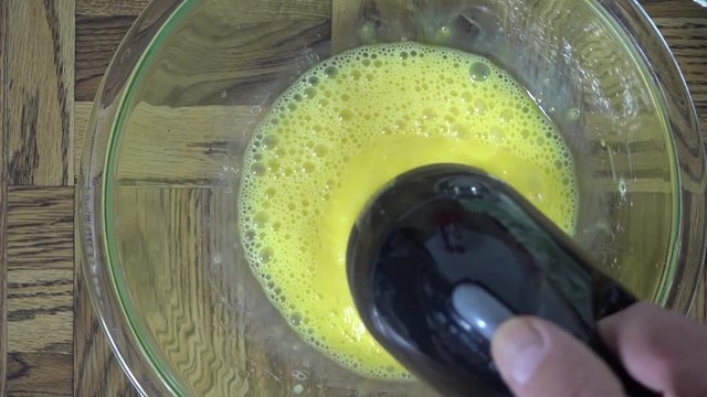 Overhead view of beating eggs in a bowl with a hand mixer