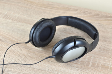 Black headphones with a cable set on a wooden desk
