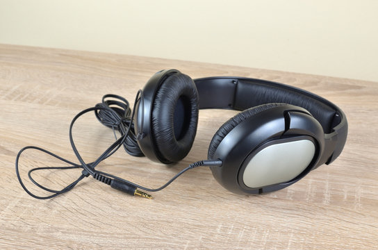 New black headphones with a cable set on a wooden desk