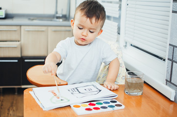 Charming baby in a child seat, draws and