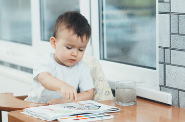 Charming baby in a child seat, draws and