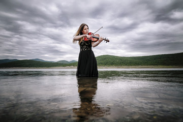 Female viola player on the lake shore