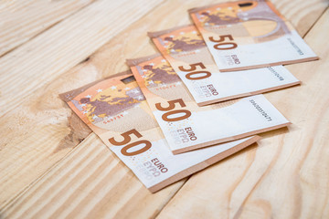 50 new euro banknotes on wooden desk