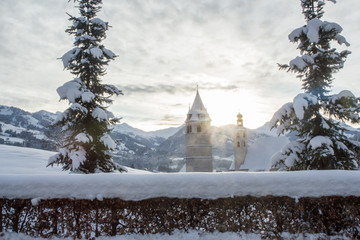 Blick auf die Pfarrkirche Kitzbühel im Winter mit Sonnenstrahlen - Kitzbühel, Tirol, Österreich