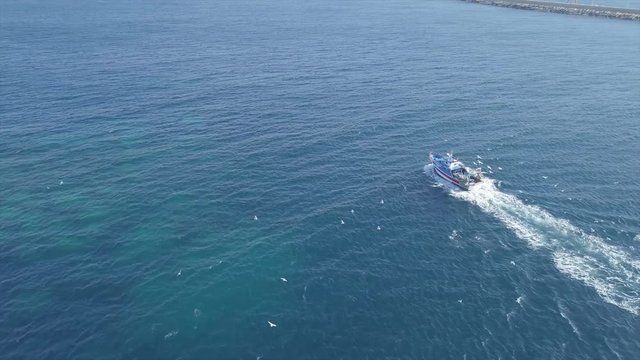 fishing boat aerial view with seagulls shot from 4k drone in mediterranean sea