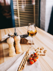 Italian sticks of grissini with a branch of cherry tomatoes and a glass of white wine on a wooden table
