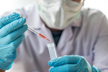 scientist or doctor dropping a blood into blood test tube in rack , research  concept