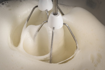 Beaten egg whites with a modern kitchen mixer used to beat the egg whites. - 186578233