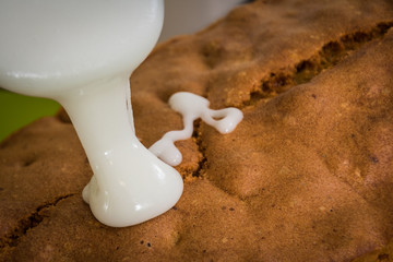 Sweet white powdered sugar icing or topping being poured onto fresh baked cake or pie from a silver spoon. - 186578496