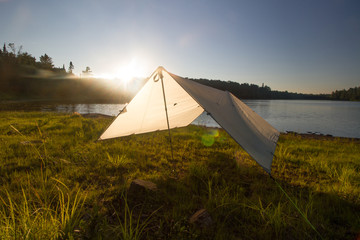 Tarp camping on lake at sunset