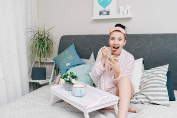 Young beautiful woman has breakfast in bed and eating cereals or muesli in the morning