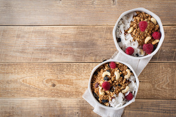 Healthy breakfast with oats granola,raspberry and nuts over wooden table