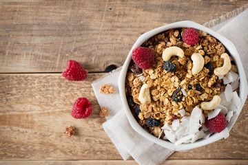 Healthy breakfast with oats granola,raspberry and nuts over wooden table