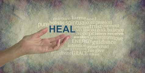 Humble Healing Words - female hand gesturing towards the word HEAL surrounded by a relevant word tag cloud on a rustic stone colored background with dark vignette edged border
